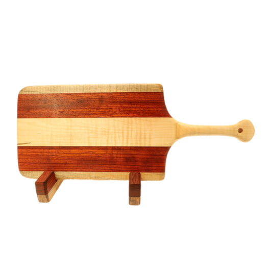 "Padauk and curly maple charcuterie board with raised handle. The board features a unique combination of warm reddish-brown padauk and light-colored curly maple, with a raised handle for easy carrying. Perfect for serving cheeses, meats, bread, crackers, fruit, and more. A stunning display piece that is sure to impress your guests."